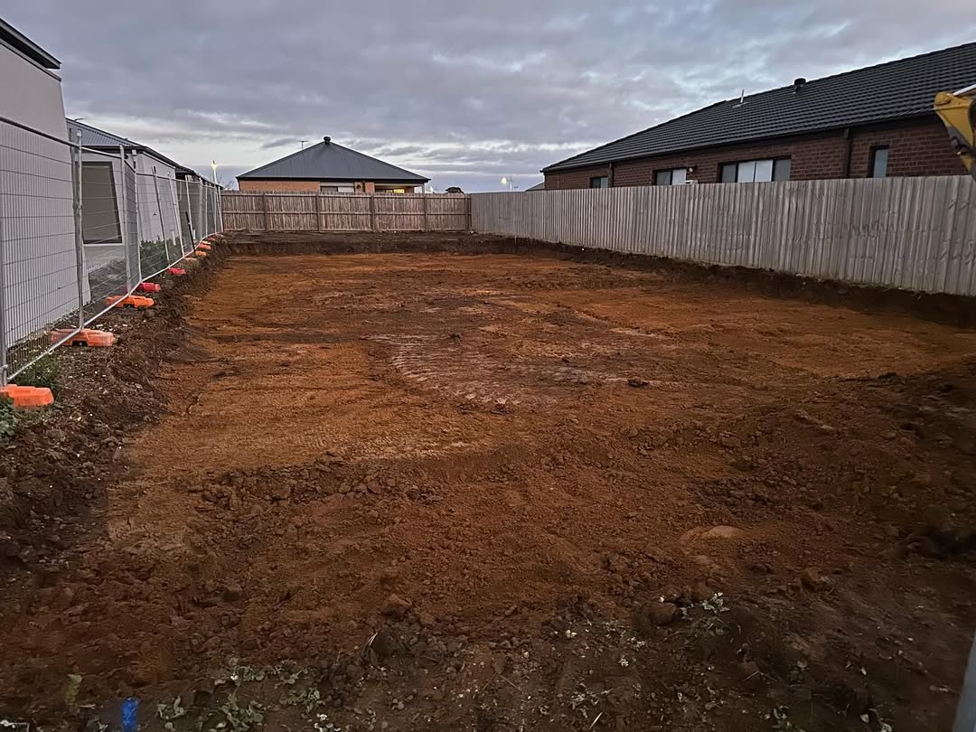 Cleared and levelled block of red-brown dirt between new houses