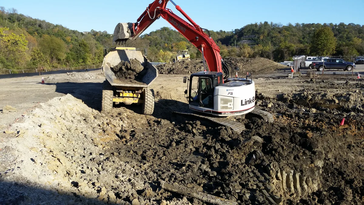 Excavator loading dirt into a dump truck on a large earthworks site